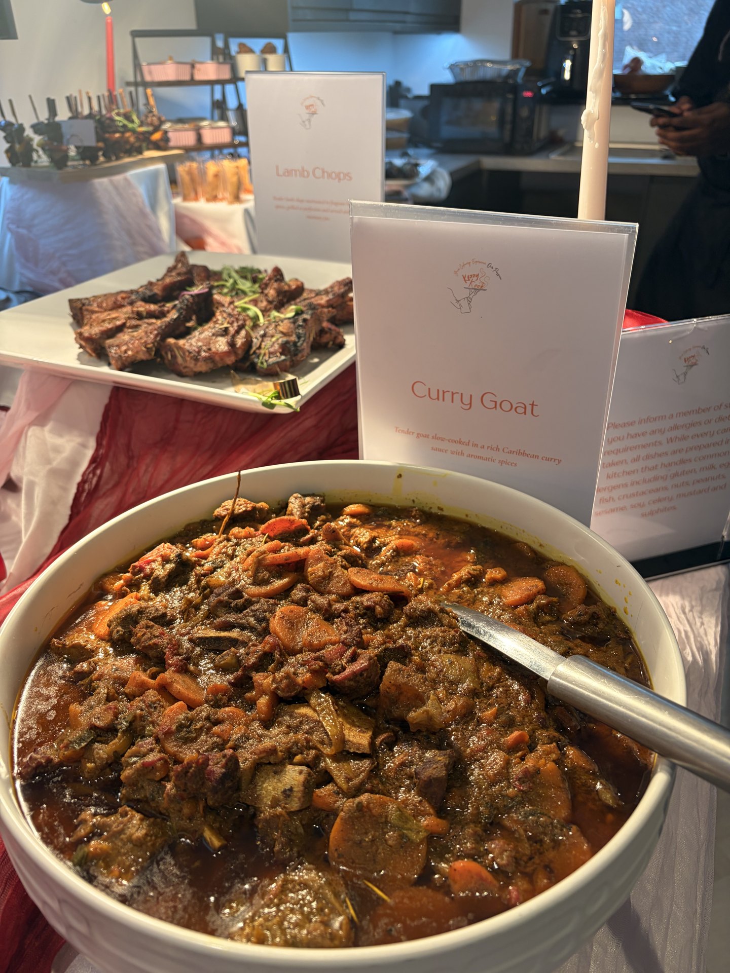 Bowl of KezzyKooks slow-cooked curry goat on a celebration buffet