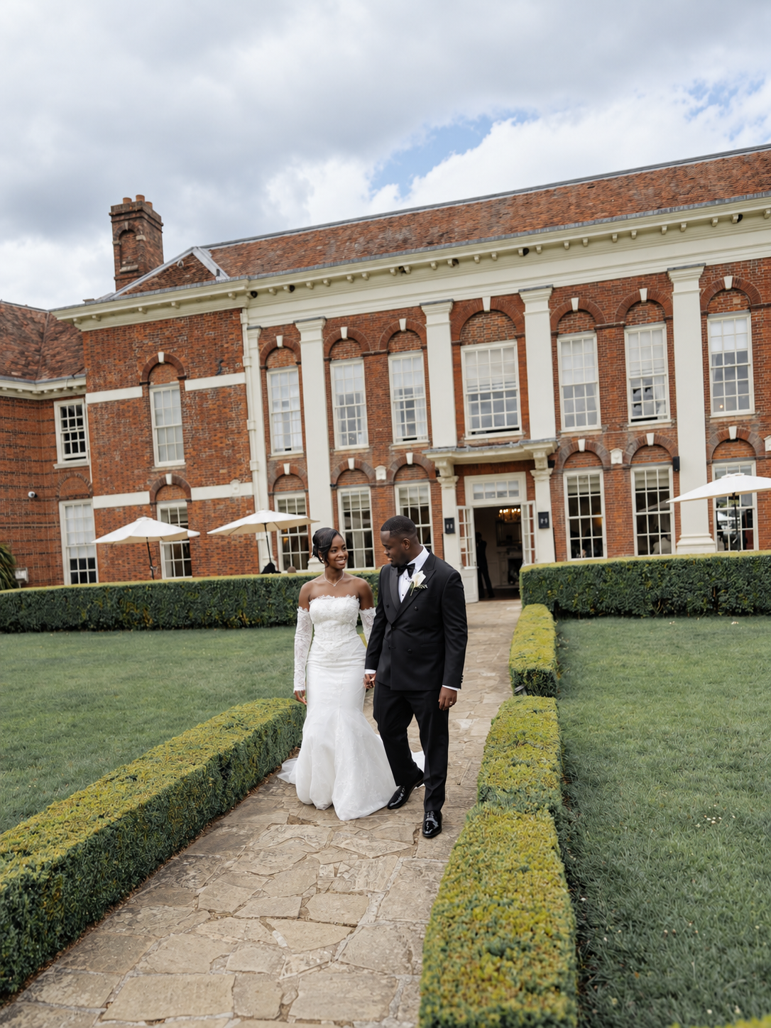 Bride and groom walking through the gardens of an English country house venue